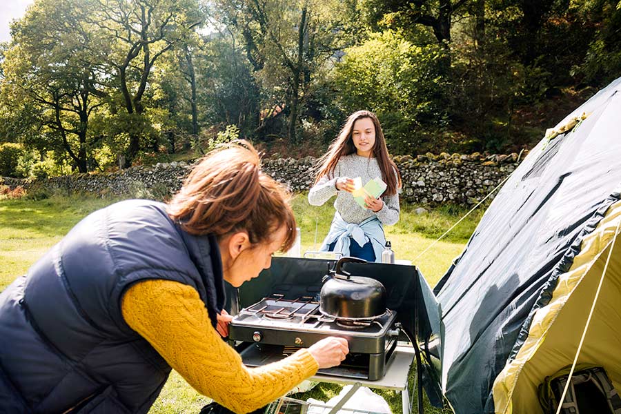 Woman at camp lighting stove to cook a meal