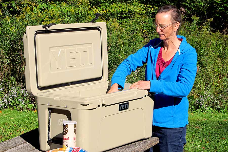 Woman getting food out of Yeti cooler on picnic table