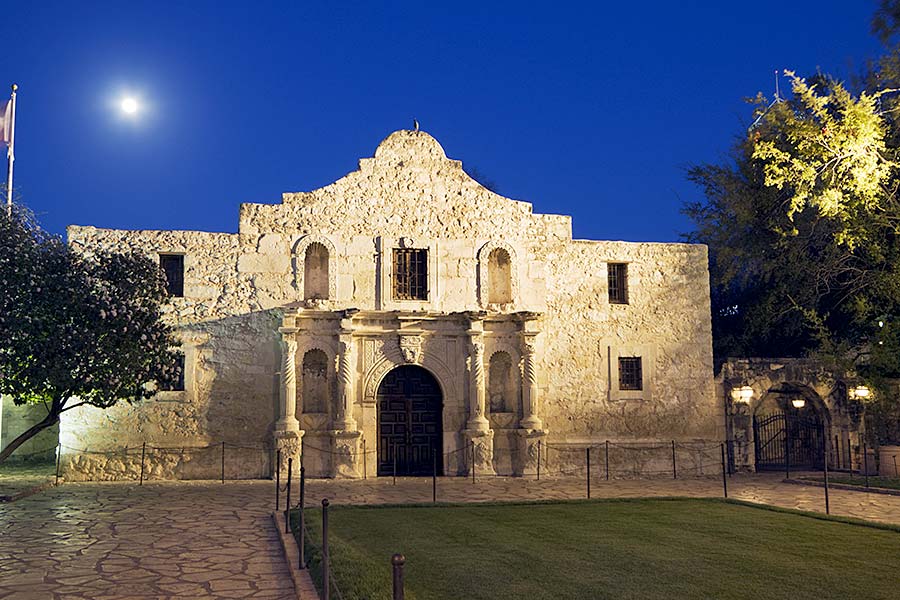 Alamo illuminated at night, full moon in sky