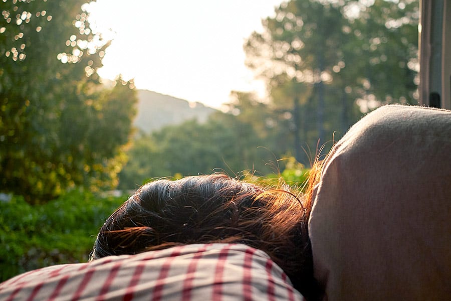 Girl laying in van looking out at trees