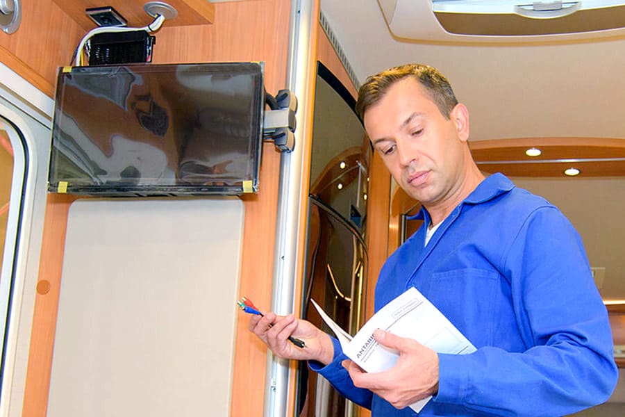 Man in blue shirt reading manual on TV installation