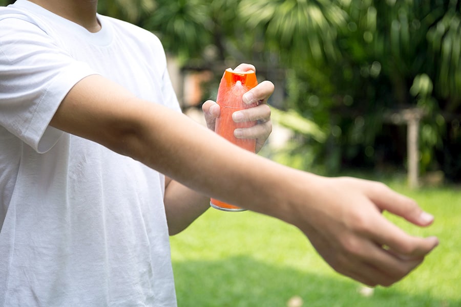 Boy spraying bug spray on his arm