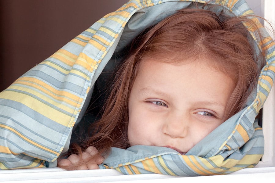 Girl looking out from under a blanket