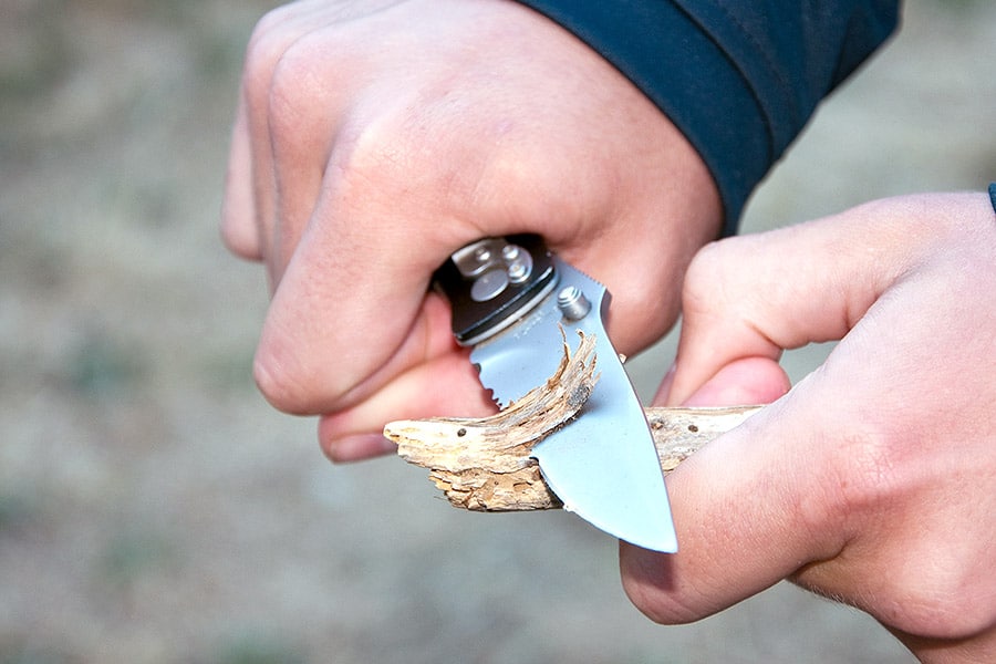 Man cutting a piece of wood with a knife