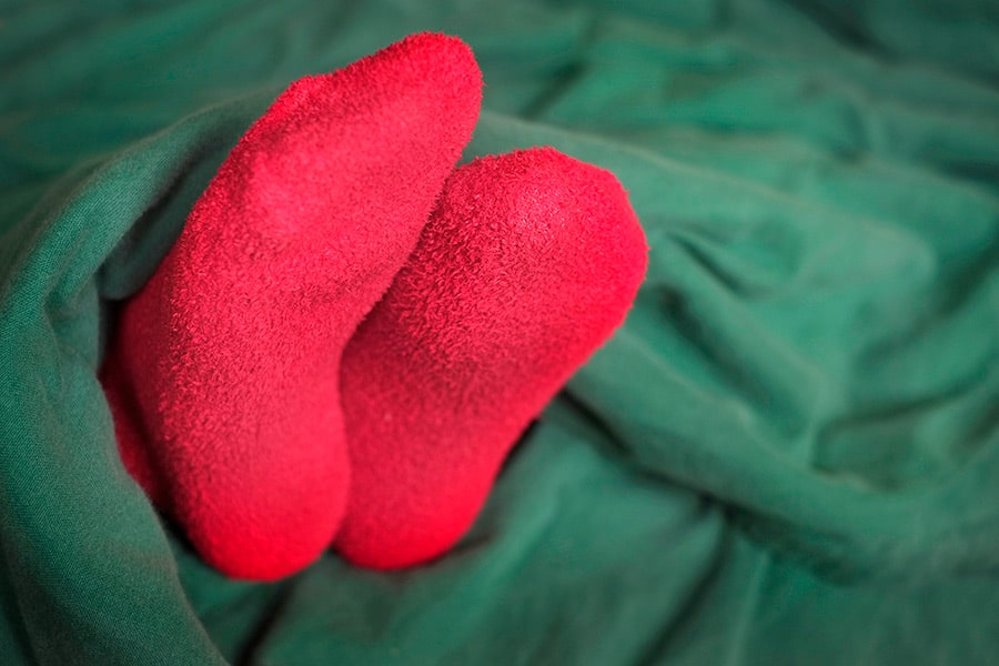 Feet with red socks sticking out from under blanket