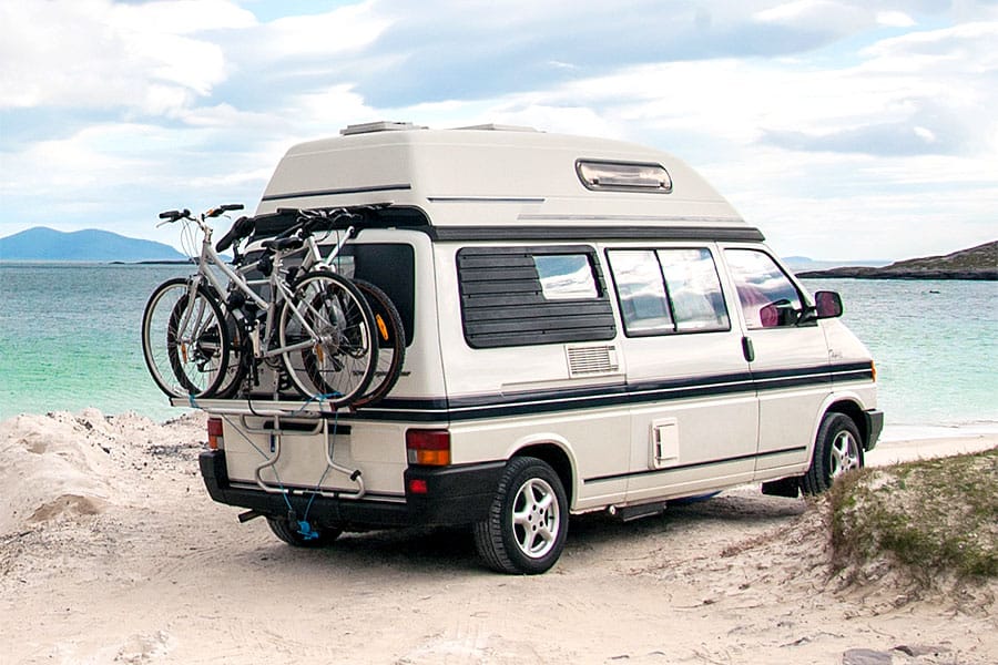Camper van with bicycles on back at ocean