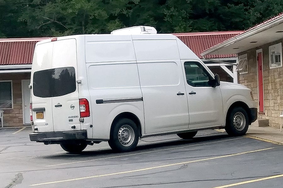 White Nissan high top van parked at restaurant