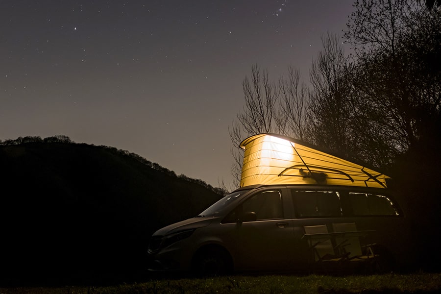 Camper van parked for the night with pop up illuminated