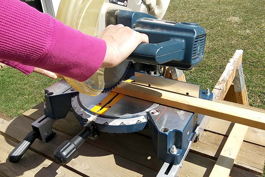 A woman cutting wood with a chop saw