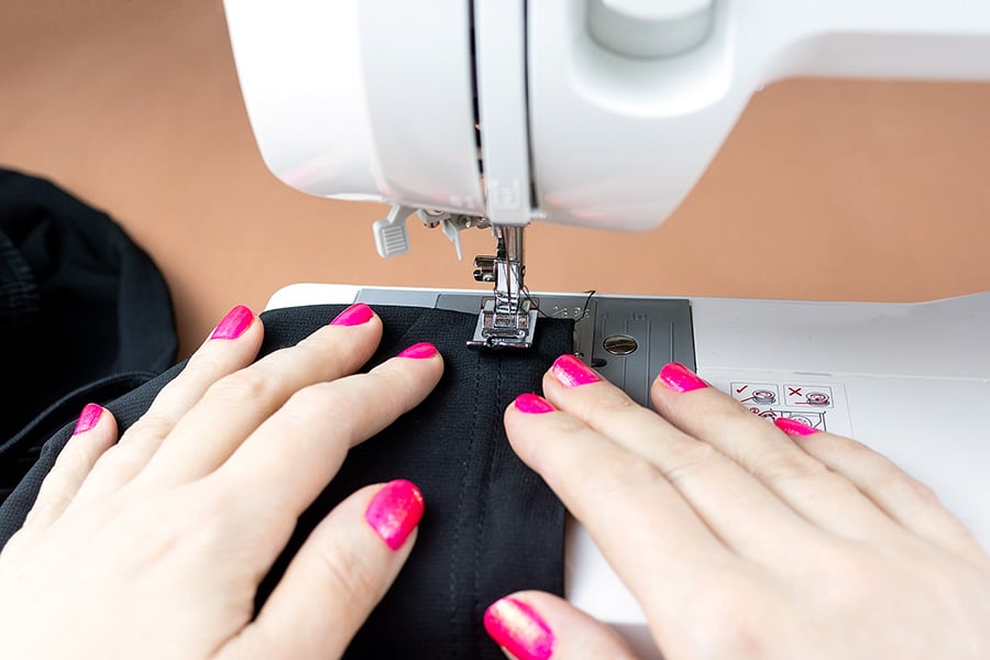Woman sewing black fabric on a sewing machine