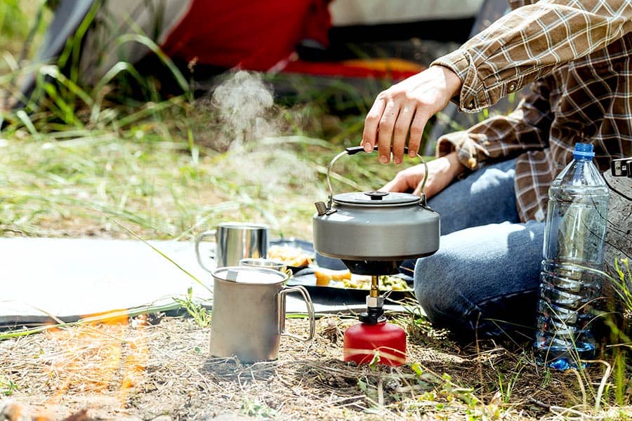 A person camping and cooking their meal with a camp stove