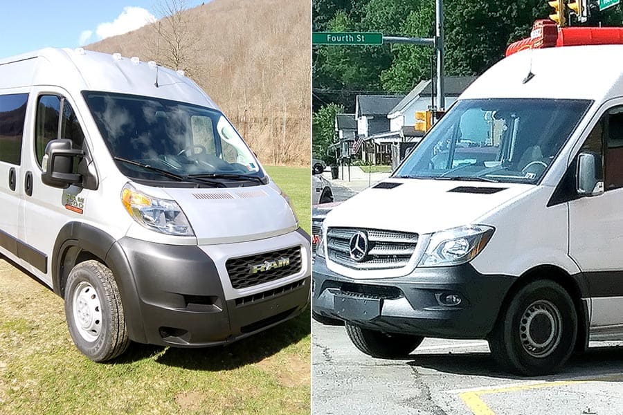 A silver van on the left on the grass and a white van on the right parked in a parking space