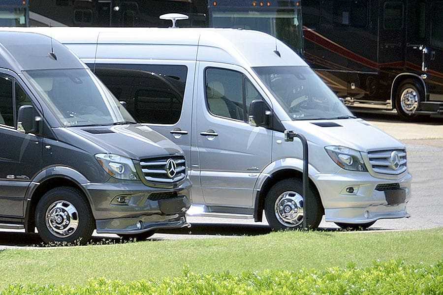 Two Class B RVs parked at a RV dealership