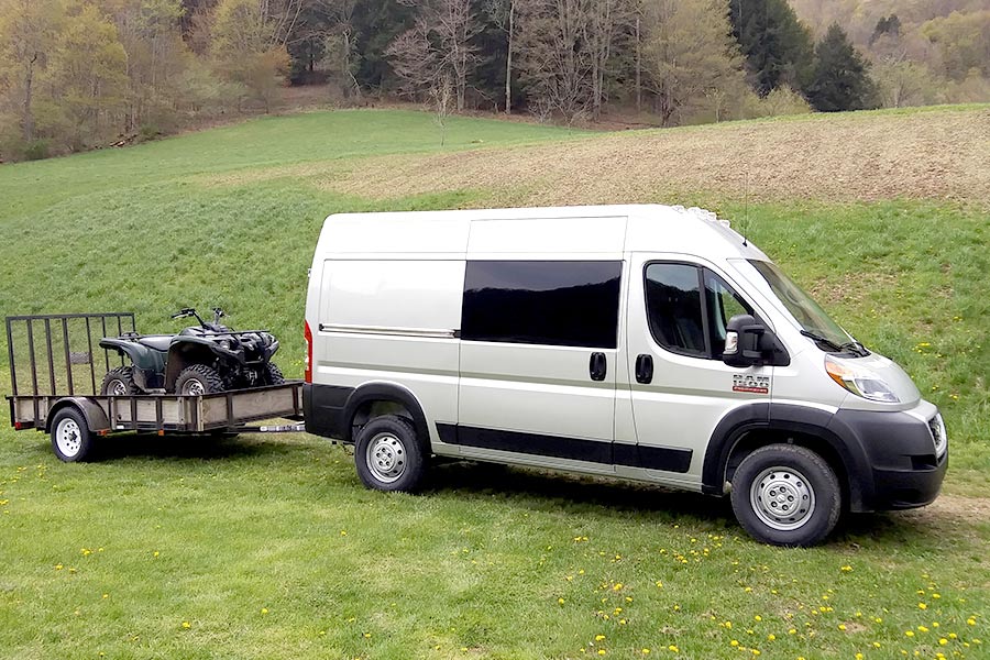 Silver van towing trailer with ATV on it