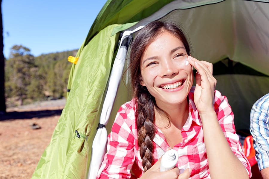 Woman in a tent applying sunblock on a sunny day