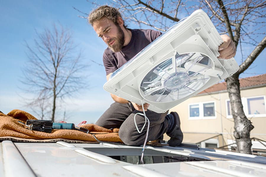 Man installing roof vent fan in van roof