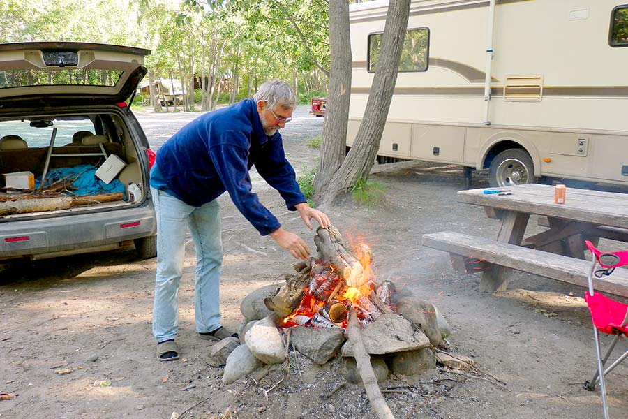Man adding wood to campfire at campground