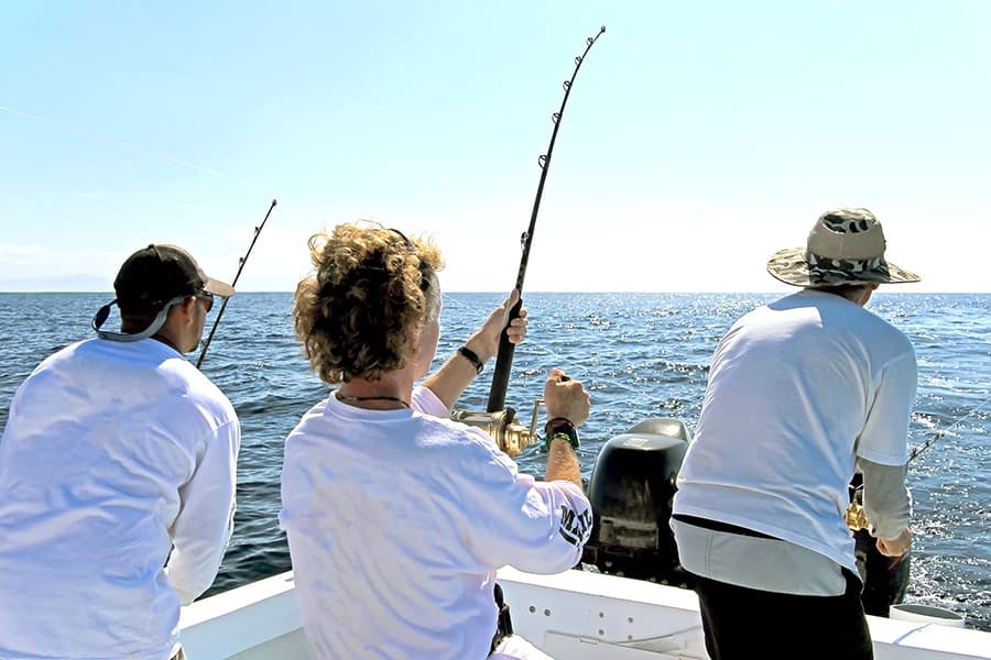 Three people on a boat fishing in the ocean
