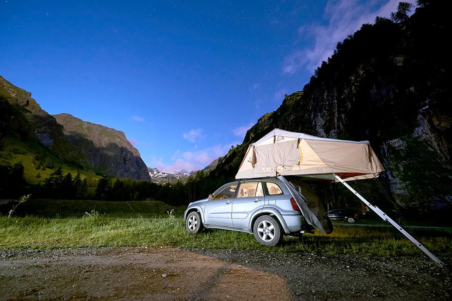 Roof top tent on car in mountain valley at dusk