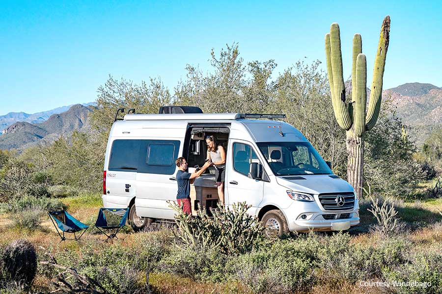 Couple in grey Winnebago Boldt van camping in the desert