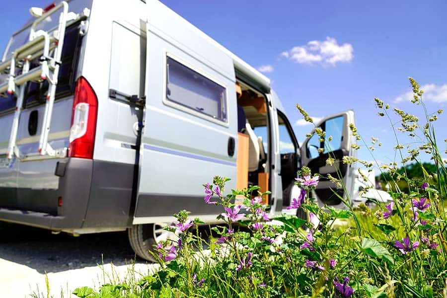 Grey camper van with doors open sitting along highway