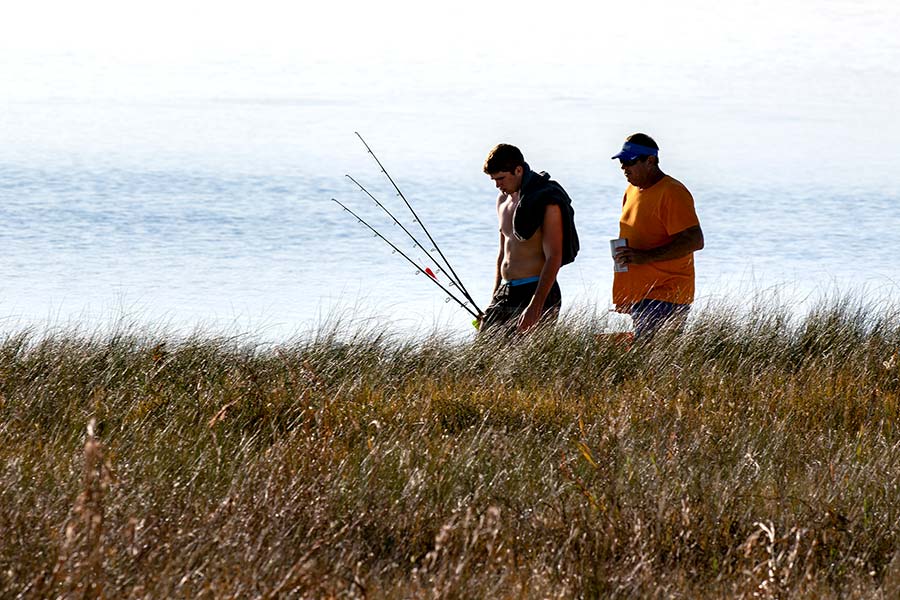 Two fishermen walking along shore