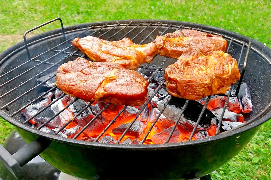 Steaks cooking on grill over lump charcoal