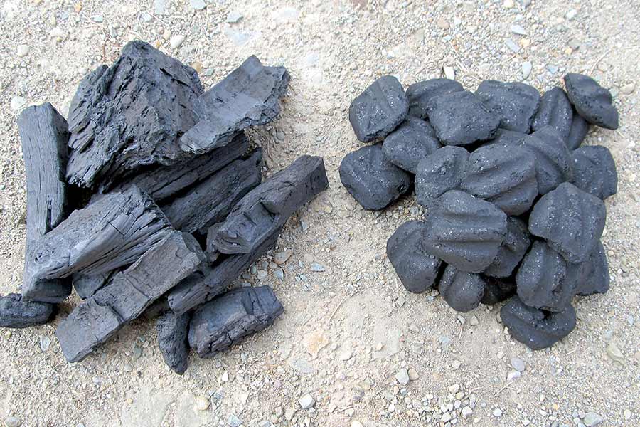 Lump charcoal and charcoal briquettes on ground