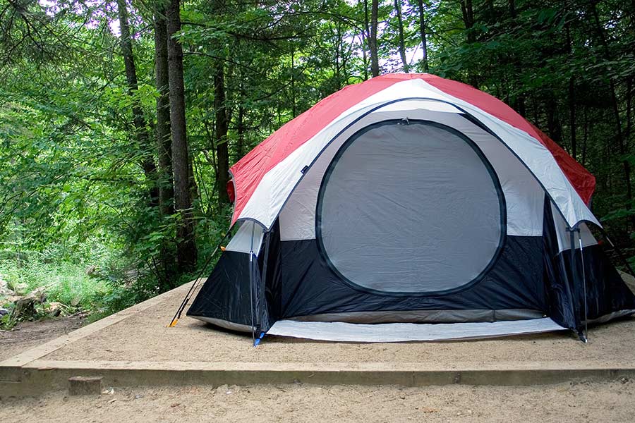 Multi colored tent on tent pad in campground next to woods