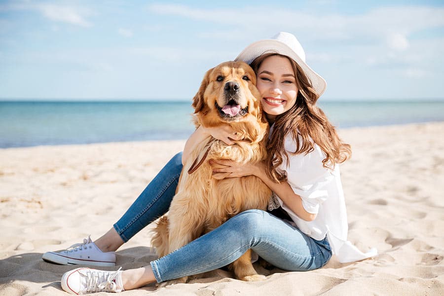 Woman sitting on beach with dog