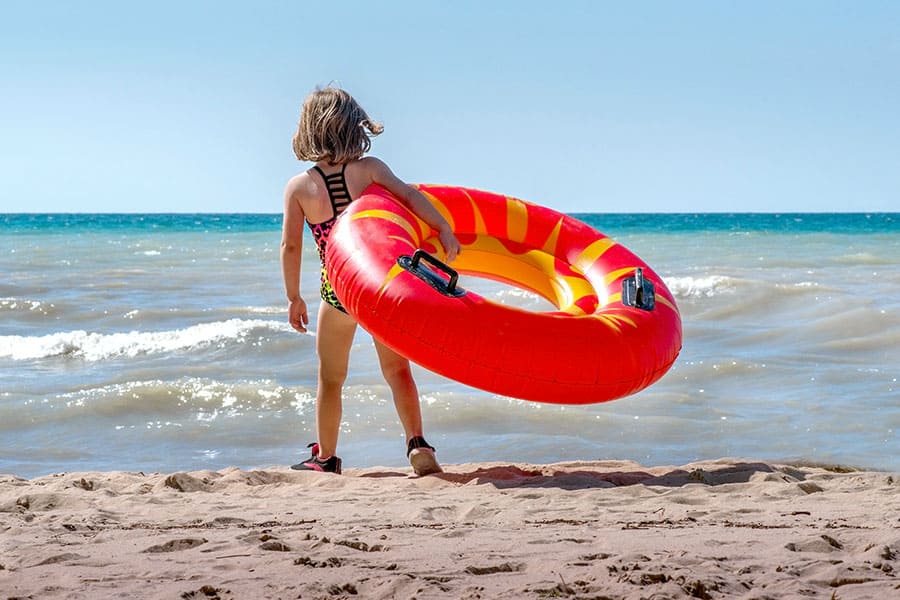 Young girl on sandy beach with red tube