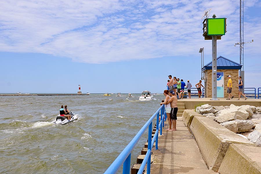 People jet skiing and boating on Lake Michigan as people watch from shore