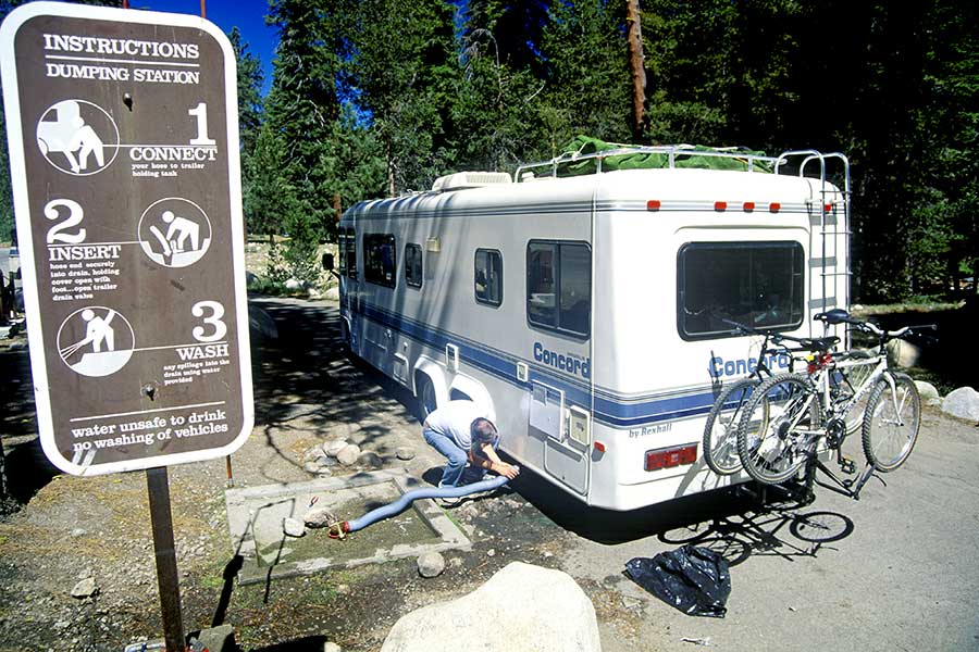 Man hooking up hose to motorhome at dump station