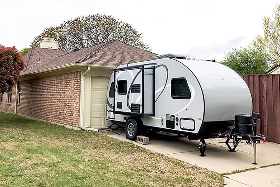 Camper trailer parked in front of a garage with a slide out open