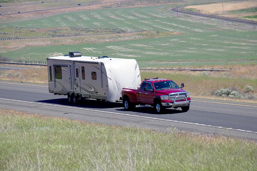 Red truck pulling camper trailer on highway