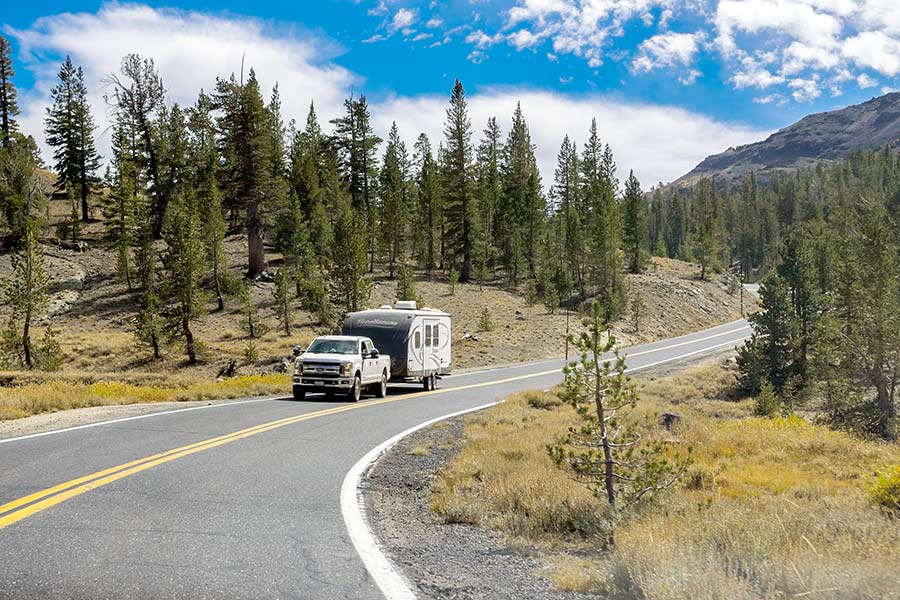 White truck towing camper trailer on blacktopped highway