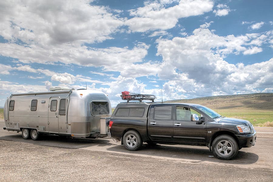 Black truck pulling silver camper trailer