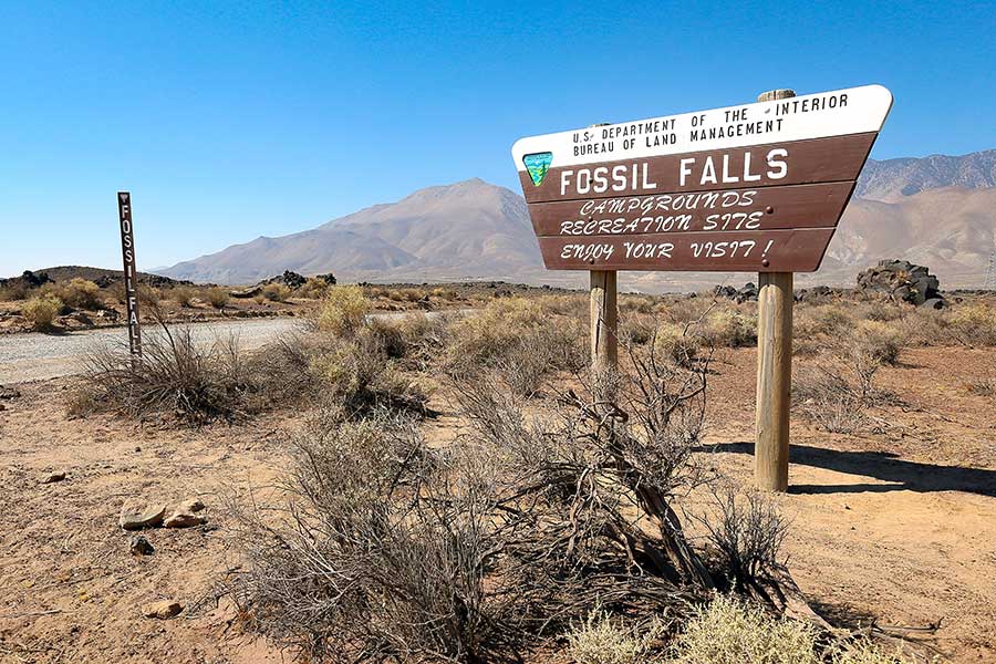 Wooden Fossil Falls sign in desert landscape