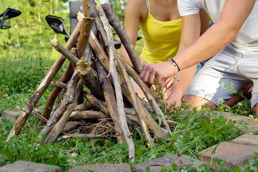 Couple building a teepee campfire