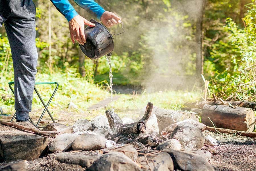 Man pouring water over campfire