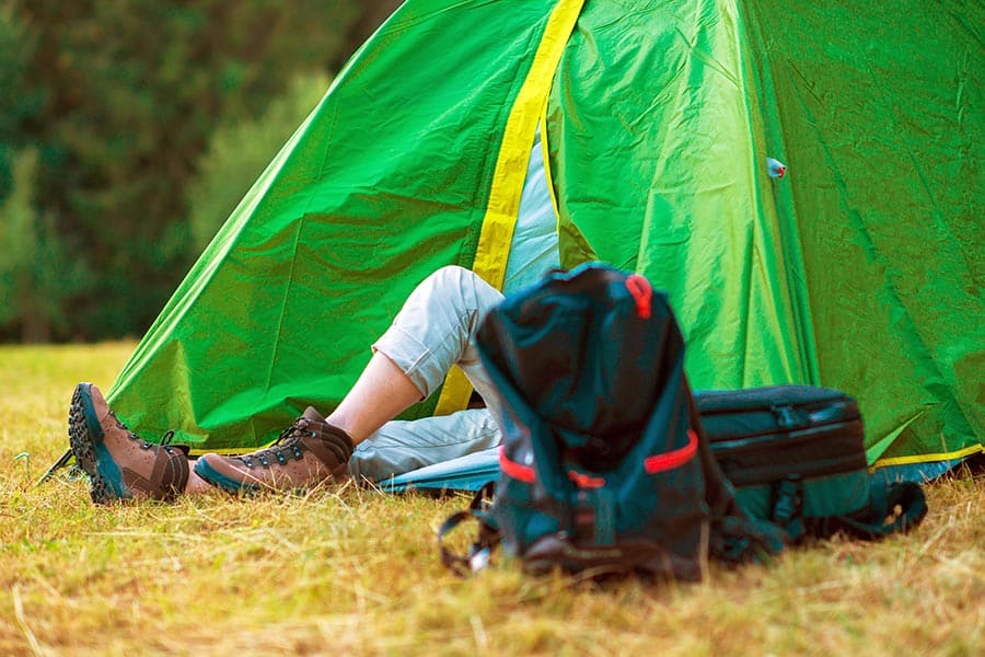 Hiker resting in green tent in meadow