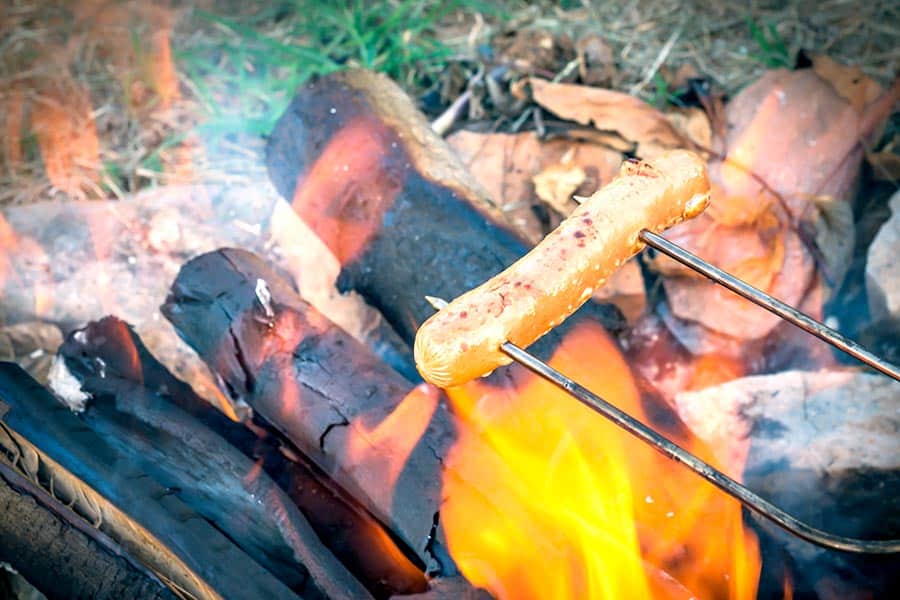 Roasting a hotdog over campfire