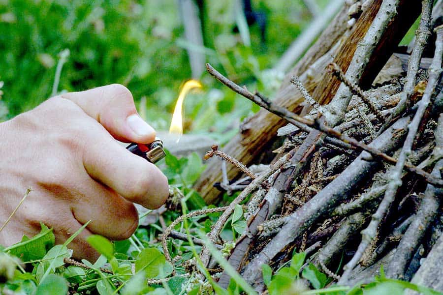 Man using a lighter to start a campfire