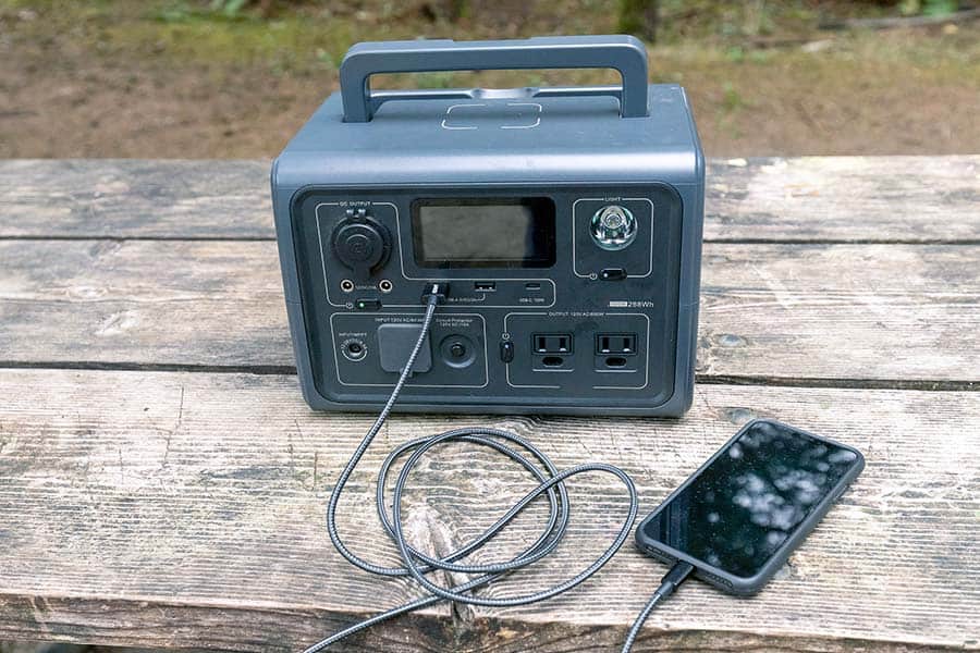 Solar Generator sitting on picnic table charging a smartphone