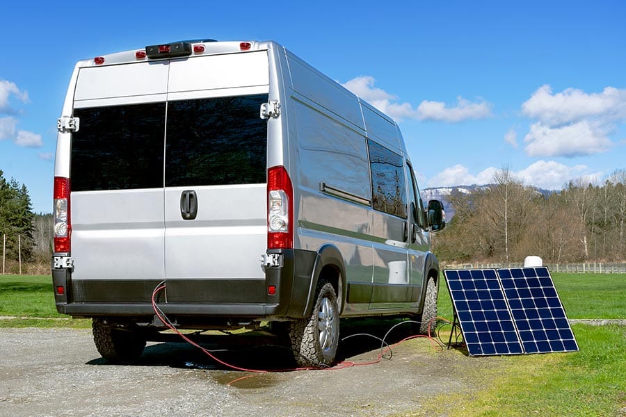 Parked van with portable solar panel along side collecting the suns rays