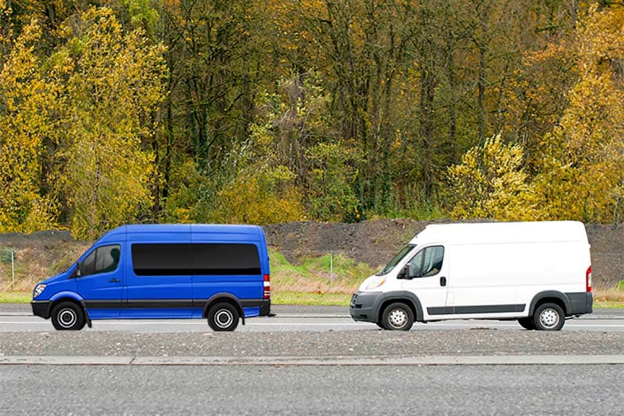 Blue passenger van followed by a white cargo van