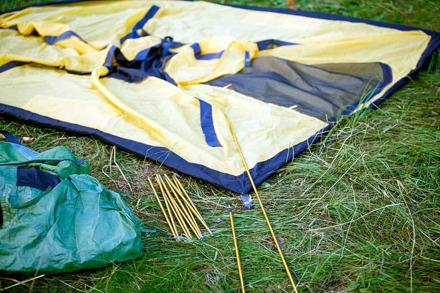 Yellow tent laying in grassy field