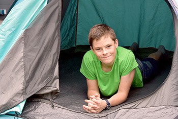 Boy looking out tent door