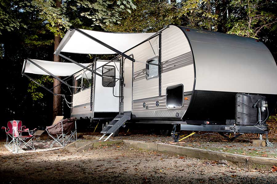 Modern camper trailer parked at forest campsite
