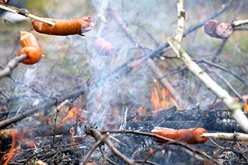 Hotdogs on sticks over fire